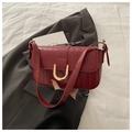 Detail der burgunderroten Tasche mit Krokodilprägung und goldener U-Metallschnalle - Rot