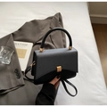 Detail of a minimalist square crossbody bag with textured patchwork and gold magnetic buckle - Black