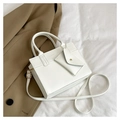 Detail of white minimalist handbag with small envelope charm on a wrinkled fabric background - White
