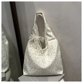 Detalle de bolso tote de lona con flores y lazo de encaje blanco en fondo minimalista - Blanco con colgante