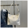 Close-up of white patent leather bucket bag with silver bow detail and knotted strap - White (Without Charm)