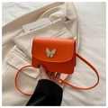Detailansicht der orangefarbenen Mini-Tasche mit weißem Schmetterling auf beigem Blazer - Orange