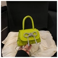 Detailed close-up of a neon green handbag featuring a sparkling silver rhinestone bow detail - Green