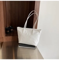 Detailaufnahme einer weißen geflochtenen Tragetasche mit minimalistischen Schultergurten - Weiß