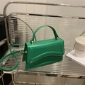 Green PU leather crossbody bag with wavy flap design and gold hardware on display - Green