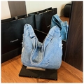 Détail d'un sac bandoulière en denim bleu délavé avec bords effilochés et reflet miroir - Bleu clair