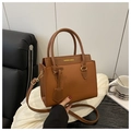 Close-up of brown pebbled leather texture and golden FASHION logo on a square handbag - Brown