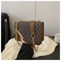 Détail du sac bandoulière à motif vintage avec chaîne dorée et finitions en cuir brun - café