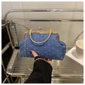 Close-up of vintage blue denim frame bag with gold engraved clasp and metal chain - Blue