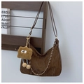Détail d'un sac hobo marron plissé avec chaîne dorée et peluche sur support en bois - Café Avec Pendentif Lapin
