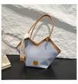 Detail of light blue denim tote with V-shape opening, brown leather trim and fashion tag - Blue