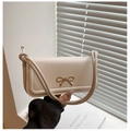 Detail of cream-white baguette bag featuring a gold bow buckle and knotted leather strap - White