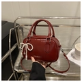 Detail view of red oil wax leather boston bag with pearl bow and logo text - Red