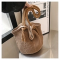 Detalle de bolso saco trenzado con asas de cuerda gruesa y adornos de borlas bohemias - Caqui