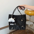 Borsa tote nera plissettata con farfalle e tracolla intrecciata in un ambiente vivace - Nero Con Pendente A Coniglio