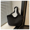 Minimalist black canvas tote bag shown in soft window light with striped shadows - Black