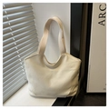 Close-up of cream white canvas tote bag with textured fabric and minimalist handle details - White
