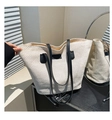 Détail de la texture gaufrée et des anses en cuir noir d'un sac cabas beige - Noir