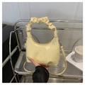 Detailed shot of a pale yellow pleated handle bag with fashion and bags lettering - Yellow