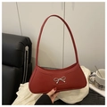 Detail of red leather baguette bag featuring a silver bow buckle on white fabric - Red