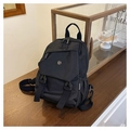 Detalle de mochila de nailon negro con cierre de solapa y hebillas sobre mesa de madera - Negro