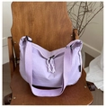 Detail of lavender crescent bag with woven zipper pulls on a rustic wood seat - Purple