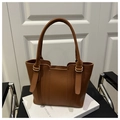 Detailed macro view of brown pebbled leather texture and golden ring hardware on handbag - Brown