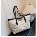 Elegante borsa tote crema con fiocchi neri e trama trapuntata su mobiletto nero - Bianco