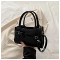 Detail showing the black leather handbag with a fixed bow and silver metal buckle accent - Black