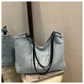 Détail d'un grand sac cabas en denim bleu clair avec broderie Hello et anses en cuir noir - Bleu clair