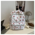 Detail eines weißen Canvas-Rucksacks mit Kirschprint und goldenen Reißverschlüssen - Kirsche