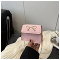 Close-up of pink mini square bag featuring a golden bow buckle and chain strap - Pink