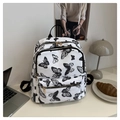 Detailansicht eines weißen Rucksacks mit Schmetterlingsdruck und goldenen Reißverschlüssen - Schwarze Schmetterlingsanhänger