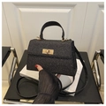 Detail of black glitter crossbody bag with square gold-tone hardware on modern chair - Black