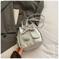 Close-up of a stylish silver mini backpack featuring a large decorative bow and thin straps - Silver