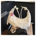 Detail of cream white pleated hobo bag with knotted strap and heart pendant accessory - With Pendant Style / White
