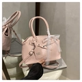 Detail of pink leather handbag featuring a white lace bow and branded hangtag on a pedestal - Pink