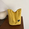 Bolso tote minimalista de nailon amarillo brillante con etiqueta en mesa de madera - Amarillo