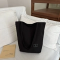 Bolso tote negro minimalista con correa al hombro en una escena de interior acogedora - Negro