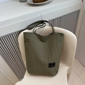 Detailed texture of green ruched nylon tote bag featuring brand logo and slim shoulder strap - Green