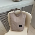 Detail shot of light brown tote bag with wrinkled texture and brand label on white seat - Khaki