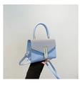 Detail view of a light blue small square handbag with textured flap and gold accents - Blue