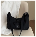Borsa tote minimalista in nylon nero con toppa logo su una sedia beige - Nero