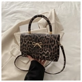 Leopard print crossbody bag with golden bow hardware and a cylindrical top handle - Brown