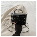 Black quilted vanity bag with silver studs and chain strap in a lifestyle setting - Black