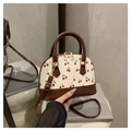 Detailansicht der cremefarbenen Kirschmuster-Tasche mit braunen Ledergriffen und Golddekor - Kaffeebraun