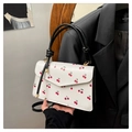 Detail of white PU square bag featuring red cherry prints and black knotted handle - White