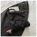 Detalle de la textura plisada del bolso negro sobre una chaqueta de traje gris - Negro