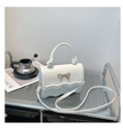 Close-up of white leather handbag with gold bow detail and stylish wavy edge flap - White