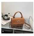 Close-up of brown leather bag with golden bow clasp and unique knotted top handle - Brown